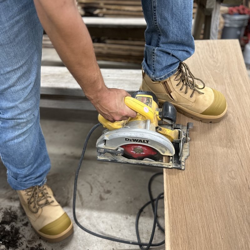 A person using a circular saw while wearing a pair of Wide Load composite toe work boots with an extra wide fit and toe box