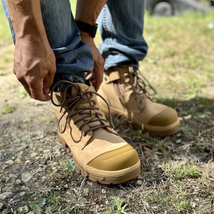 A close up of a person putting on and adjusting Wide Load composite toe work boots for extra wide feet