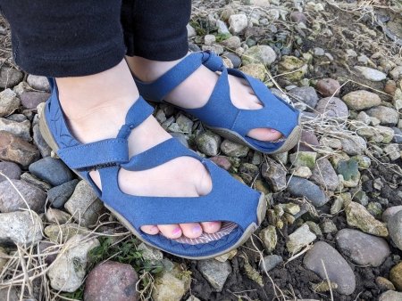 A young child's feet in Wildling Feather barefoot partially closed toe sandals with an ultra minimal flexible outsole