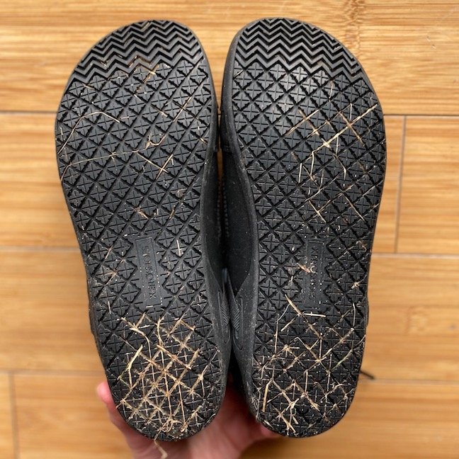 A hand holding the Xero Shoes Prio All-Day barefoot sneaker made for the service industry with the non slip soles facing up to show the natural foot shape