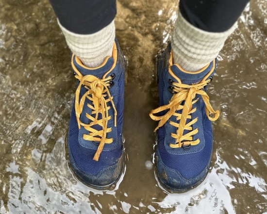 Top down view of Xero Shoes Ridgeway hiking Shoes being worn in water. You can see the speed hooks, golden laces against navy uppers, and the wide anatomical toe box