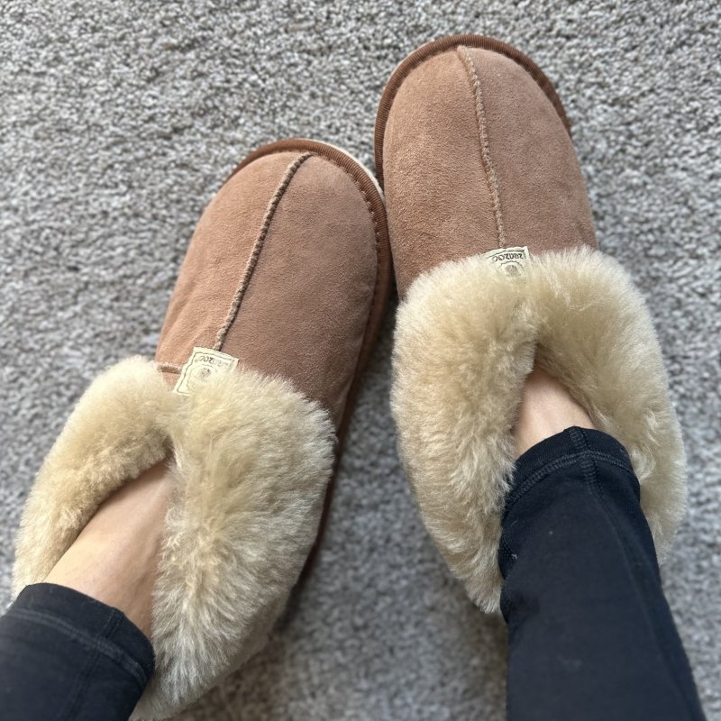 Top view of a pair of feet casually relaxed wearing Zeazoo Dolly sheepskin barefoot slippers with extra cozy warm lining
