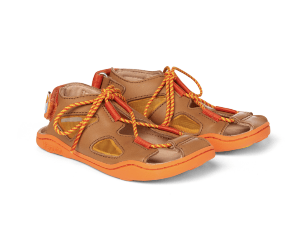 A pair of brown leather sandals held together at the top with yellow and red striped laces with red leather details and a Velcro heel. Featuring an orange sole. Shown on a white background.