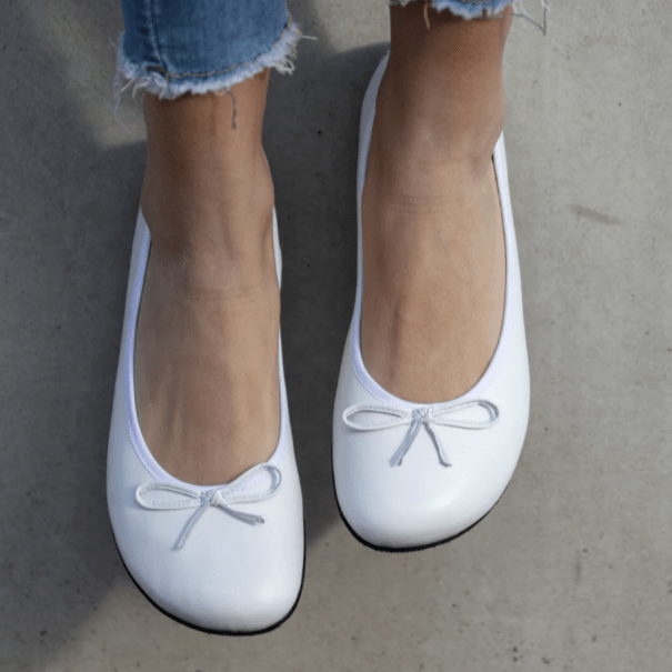 A close up pic of Zaqq white barefoot ballet flats with a small bow detail